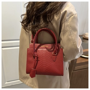 Close-up of red woven texture handbag with gold fashion lettering and adjustable strap
