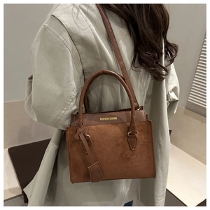 Close-up of brown patchwork tote bag in textured suede and smooth leather with gold text