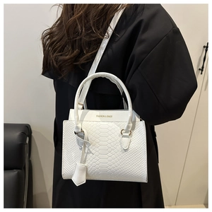 Nahaufnahme der weißen Handtasche mit Krokodilprägung, goldenem Metallring und Riemen