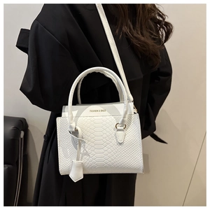Detailed view of white crocodile pattern leather bag with Fashion & Bags text on black coat
