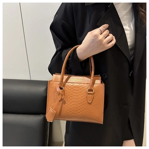 Close-up of brown crocodile texture on leather handbag with fashion logo detail