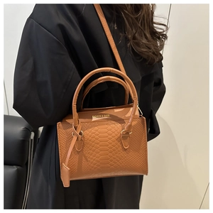 Detail of warm brown crocodile pattern leather bag with gold Fashion & Bags lettering