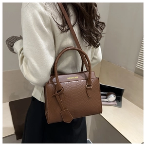 Details der Krokodilprägung auf brauner Ledertasche mit goldenem Fashion-Logo