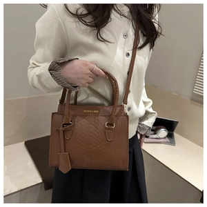 Detailed view of the brown embossed faux leather texture and gold hardware on the bag