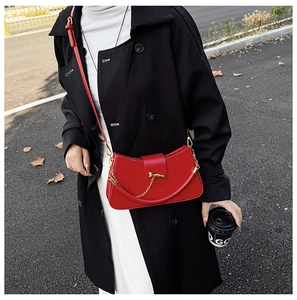 Detail view of red leather box bag with gold metal hardware on model in black coat