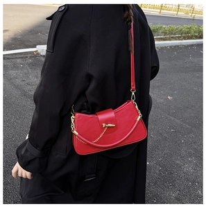 Street style shot of a luxury red half-moon leather crossbody bag with gold chain accents