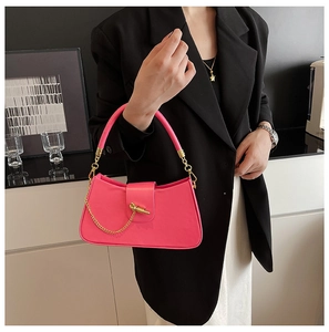 Detail of bright pink handbag featuring a unique gold metal clasp and chain accent