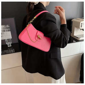Pink leather handbag detail featuring golden key-shaped lock and chain with black suit