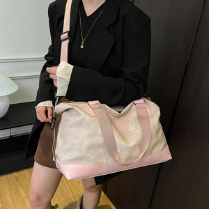 Large beige canvas travel bag with pink leather trim and adjustable shoulder strap