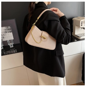 Detail of beige geometric shoulder bag with gold chain and metal buckle on a model