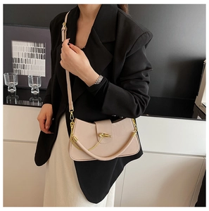 Detail of beige leather crossbody bag featuring a unique gold knot buckle and metal chain
