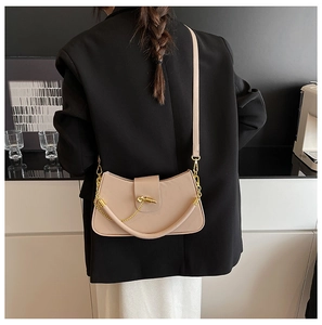 Detail of elegant beige crossbody bag with gold chain lock and smooth leather texture
