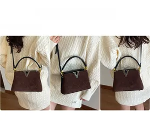 Detailed close-up of dark brown quilted suede bucket bag with gold metal V-buckle and strap
