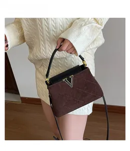 Detail of dark brown quilted suede handbag with gold V-logo and black top handle