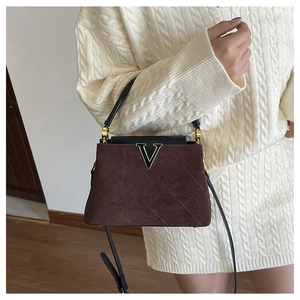 Detail of vintage quilted brown suede bucket bag with gold V buckle and black trim