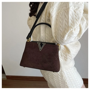 Detail view of brown quilted suede bucket bag with gold metal V logo and top handle