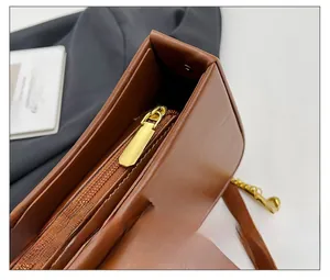 Detailed macro view of smooth golden zipper and stitching on dark brown leather crossbody bag