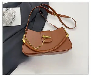 Detail of brown leather saddle bag with knot gold buckle and metal chain accent