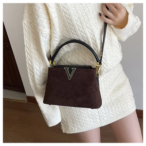 Detailed view of quilted coffee suede handbag featuring a gold V logo and leather handle