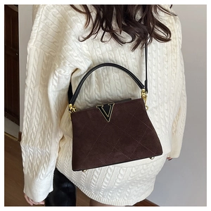 Close-up of quilted suede bucket bag featuring V-shaped metal logo and gold-tone hardware