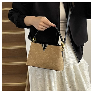 Detail of brown quilted matte handbag with golden V-logo and black leather handle