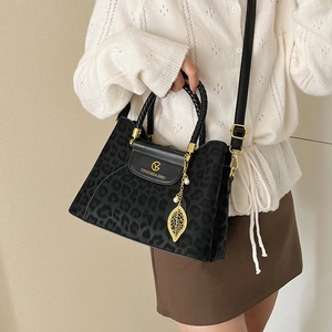 Sac seau à motif léopard avec poignée tressée et breloque feuille d'or porté par modèle