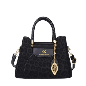 Sac à bandoulière léopard noir avec détails dorés et poignée tressée sur fond blanc