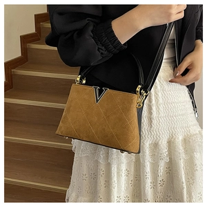 Detail of brown suede bucket bag featuring quilted pattern and gold V-shaped metal hardware