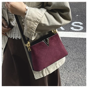 Detail of burgundy suede bucket bag with quilted rhombus pattern and gold V logo