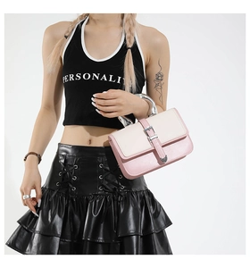 Detail of a pink and white patchwork handbag featuring a glossy silver curved metal handle