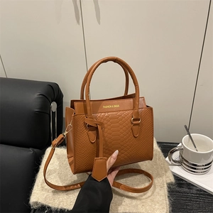 Brown crocodile embossed tote bag with gold lettering on a soft textured rug