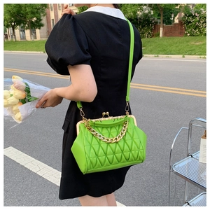 Detail of green quilted handbag featuring a golden frame closure and chunky chain strap