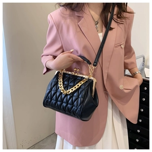 Detail of black quilted shell bag with gold chain strap worn by a model in pink blazer