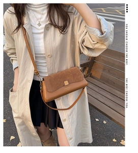 Brown leather baguette bag worn by model in an autumn urban street setting with golden buckle