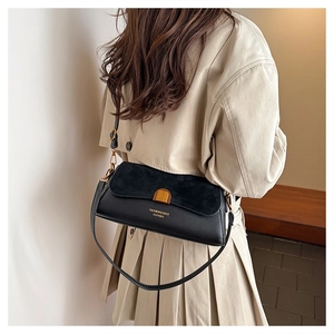 Close-up of black leather baguette bag with gold buckle on a woman's shoulder