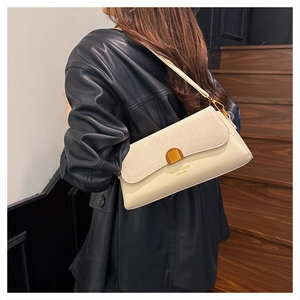 Detail of cream flap baguette bag featuring suede texture and gold buckle on a model