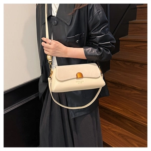 Detail of cream flap bag showing leather and suede patchwork with gold buckle clasp