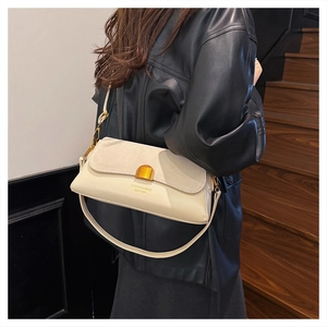 Close-up of matte leather and suede stitching detail on a beige baguette shoulder bag