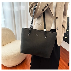 Dettaglio borsa shopper nera con trama a grana e logo argentato metallizzato lucido