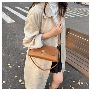 Detail of vintage brown patchwork baguette bag with gold metal buckle on street bench