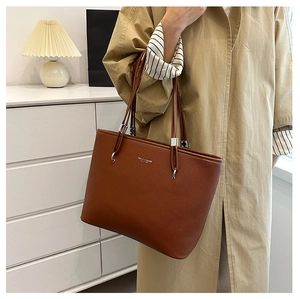 Dettaglio della borsa tote in pelle marrone con grana litchi e fibbie in metallo argento