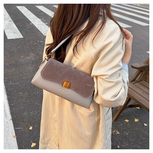 Detail of grey and brown leather shoulder bag with gold buckle on a stylish model