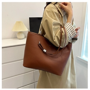 Borsa tote in pelle martellata marrone con fibbia in metallo indossata da una modella