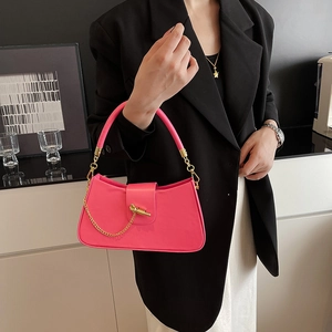 Magenta half-moon handbag with gold chain and knot buckle detail on black blazer