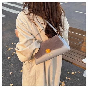 Street style shot of a vintage patchwork shoulder bag with gold clasp on a trench coat