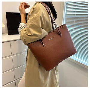 Dettaglio della borsa tote in pelle marrone con motivo litchi e tracolla metallica