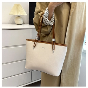 Dettaglio borsa tote in pelle litchi bianco sporco con manici marroni e logo