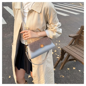Chic patchwork crossbody bag with blue leather and suede flap shown on a model