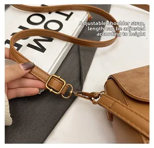Close-up of adjustable brown leather shoulder strap with gold metal buckle and hook