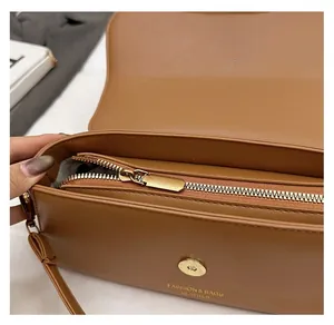 Detail of a brown leather bag showing inner zipper compartment and golden hardware